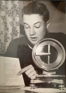 David Warner explaining systematic errors in dip circle measurements with a dip circle device in the foreground. Auckland Star, 1954.